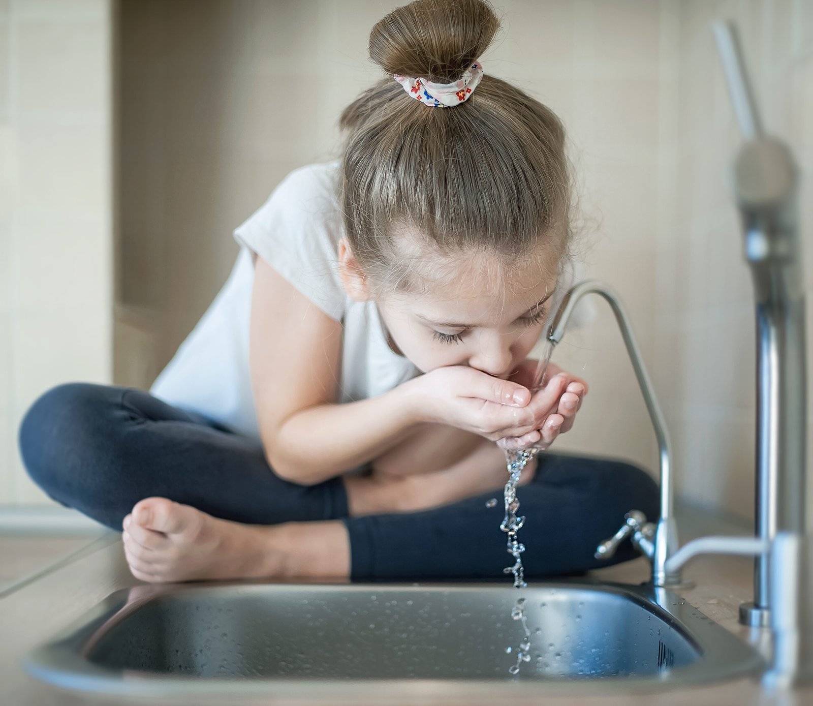 Caucasian Cute Girl Is Drinking From Water Tap Or Faucet In Kitc